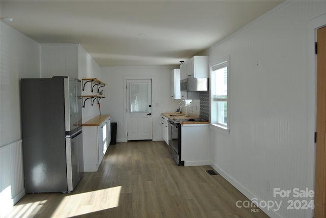 kitchen featuring butcher block counters, white cabinetry, sink, stainless steel appliances, and light hardwood / wood-style floors