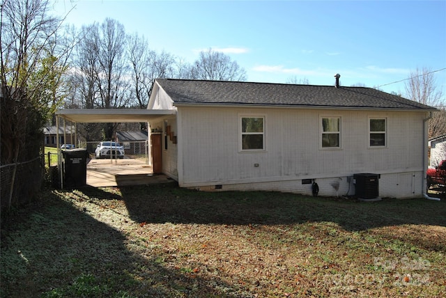 rear view of property featuring a carport, central AC unit, and a lawn