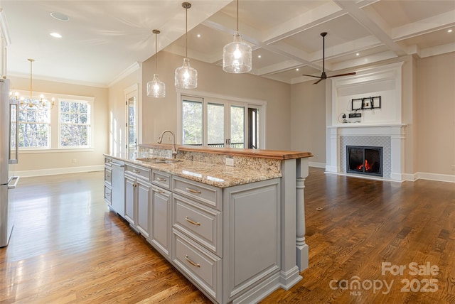 kitchen with ceiling fan with notable chandelier, a sink, open floor plan, dishwasher, and light wood-style floors