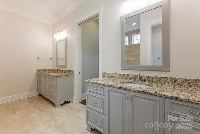 bathroom featuring crown molding, baseboards, two vanities, and a sink