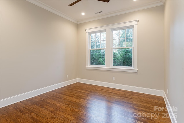 spare room with crown molding, visible vents, baseboards, and dark wood-style floors