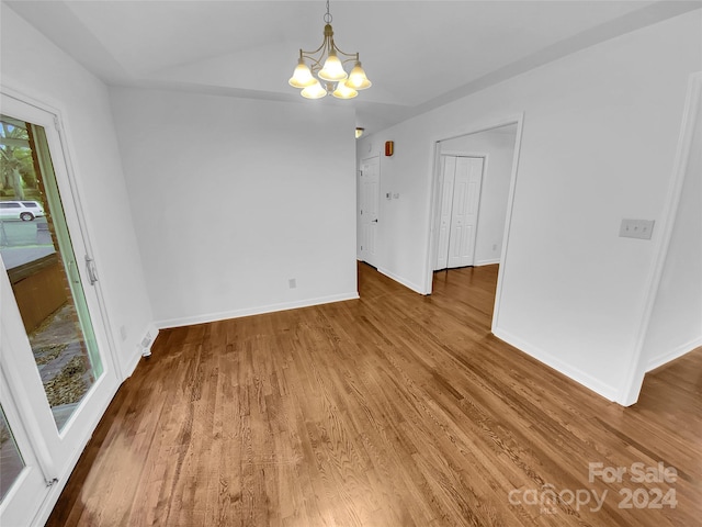 empty room with hardwood / wood-style floors and an inviting chandelier