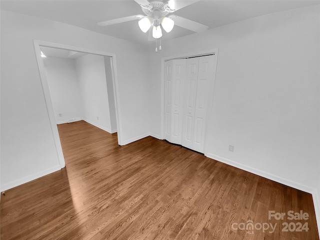 unfurnished bedroom featuring ceiling fan, wood-type flooring, and a closet