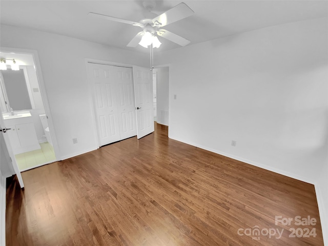 unfurnished bedroom featuring a closet, connected bathroom, dark hardwood / wood-style floors, and ceiling fan