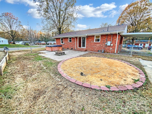 rear view of house featuring a hot tub, a patio area, and a fire pit