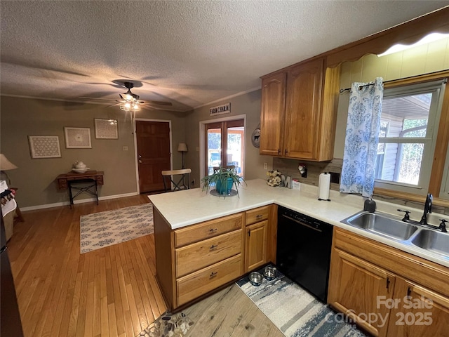 kitchen with dishwasher, sink, kitchen peninsula, a textured ceiling, and light hardwood / wood-style flooring