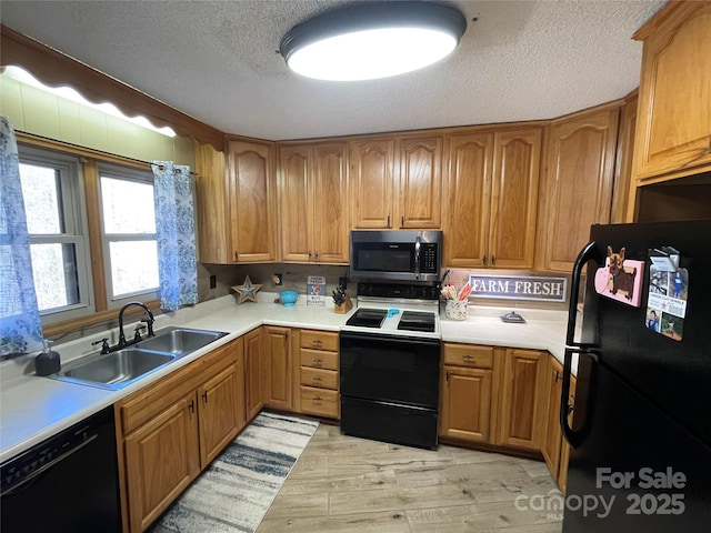 kitchen with sink, black appliances, a textured ceiling, and light wood-type flooring