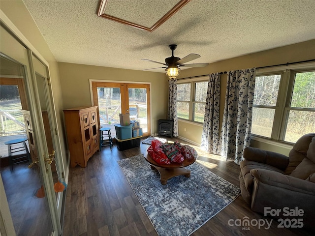 living room with ceiling fan, a textured ceiling, dark hardwood / wood-style flooring, french doors, and a wood stove