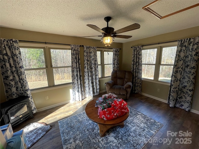 living room featuring a wealth of natural light, dark wood-type flooring, a textured ceiling, and a wood stove