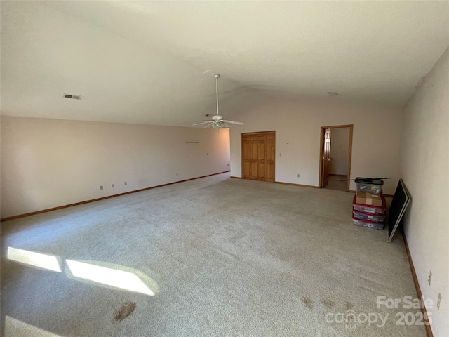 unfurnished living room with vaulted ceiling, light colored carpet, and ceiling fan