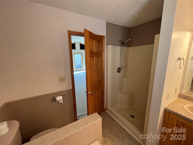 bathroom featuring vanity, tile walls, a textured ceiling, and walk in shower