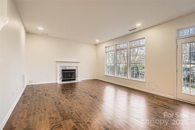 unfurnished living room featuring a high end fireplace and dark wood-type flooring