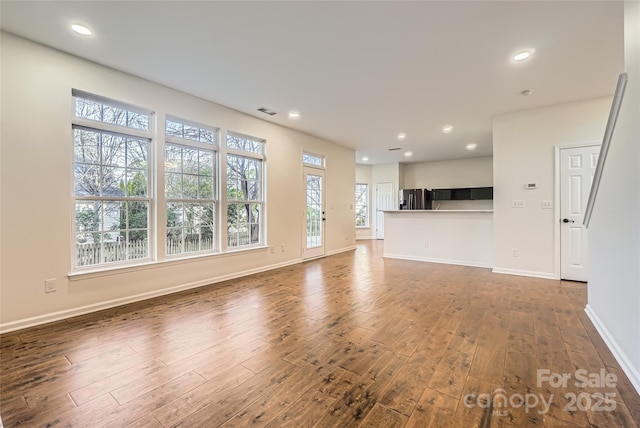 unfurnished living room with a wealth of natural light and hardwood / wood-style floors