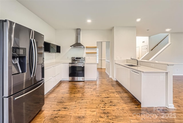 kitchen featuring white cabinetry, sink, wall chimney range hood, and appliances with stainless steel finishes