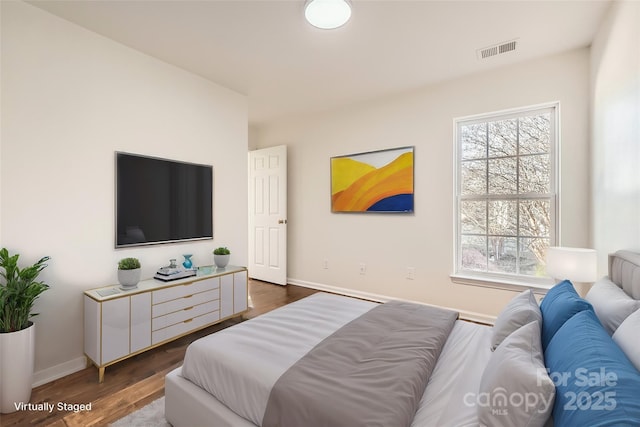 bedroom with multiple windows and dark hardwood / wood-style flooring