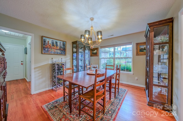 dining area with a textured ceiling, hardwood / wood-style flooring, and a notable chandelier