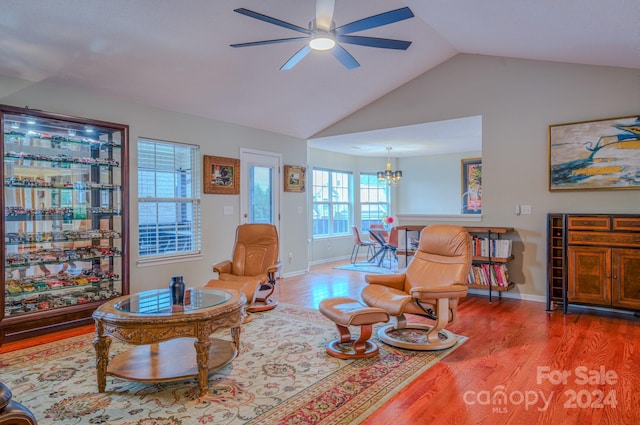 living room with ceiling fan with notable chandelier, hardwood / wood-style flooring, and vaulted ceiling