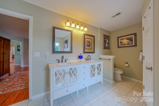 bathroom with tile patterned floors, vanity, toilet, and a textured ceiling