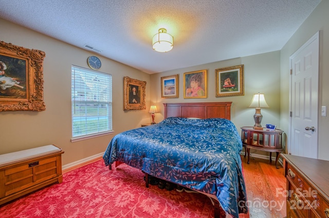 bedroom with hardwood / wood-style flooring and a textured ceiling