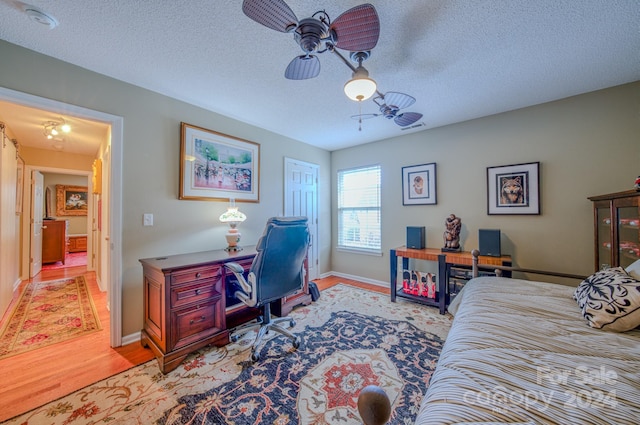 bedroom with a textured ceiling, light hardwood / wood-style flooring, and ceiling fan