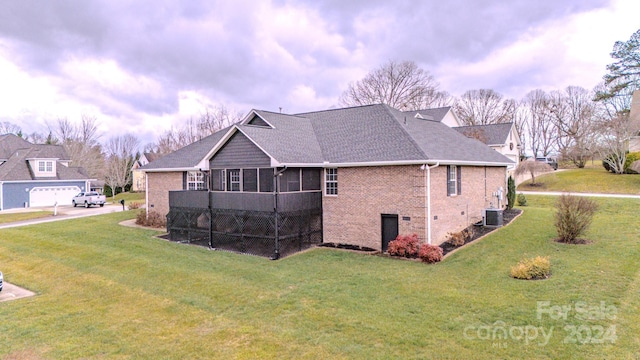 back of property featuring a lawn, a sunroom, and central AC unit