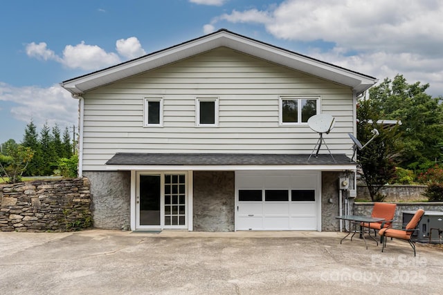 rear view of property with a garage and a patio