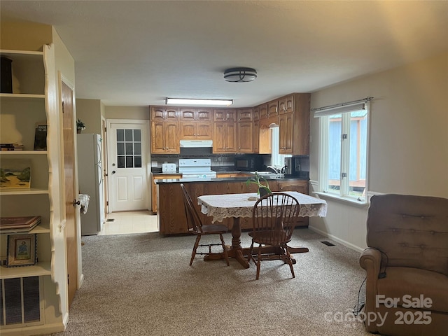 kitchen featuring white fridge, decorative backsplash, range, and light colored carpet