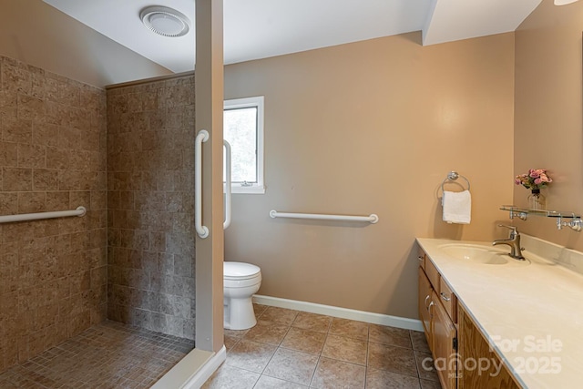 bathroom with toilet, tile patterned flooring, tiled shower, and vanity