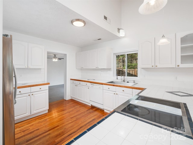 kitchen featuring tile countertops, white cabinets, white dishwasher, sink, and stainless steel fridge