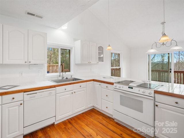 kitchen featuring tile countertops, white appliances, sink, hanging light fixtures, and white cabinetry