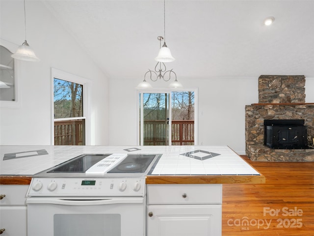 kitchen with pendant lighting, a fireplace, white cabinetry, and white electric stove