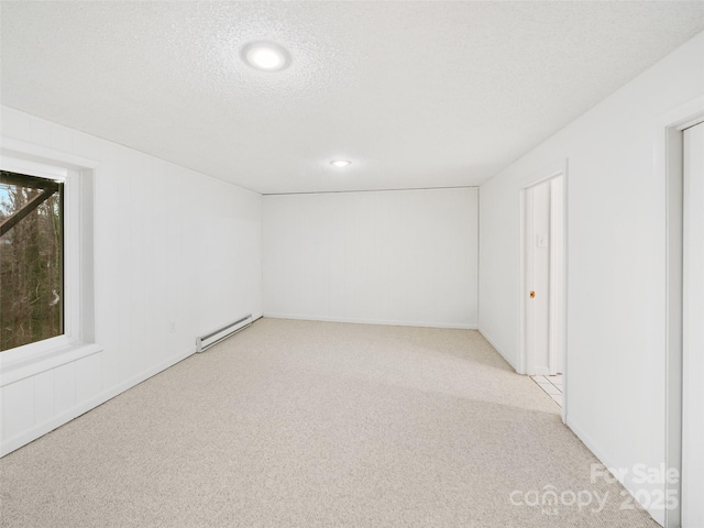 carpeted spare room with a baseboard radiator and a textured ceiling