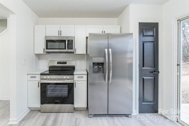 kitchen with light hardwood / wood-style flooring, white cabinetry, stainless steel appliances, and tasteful backsplash