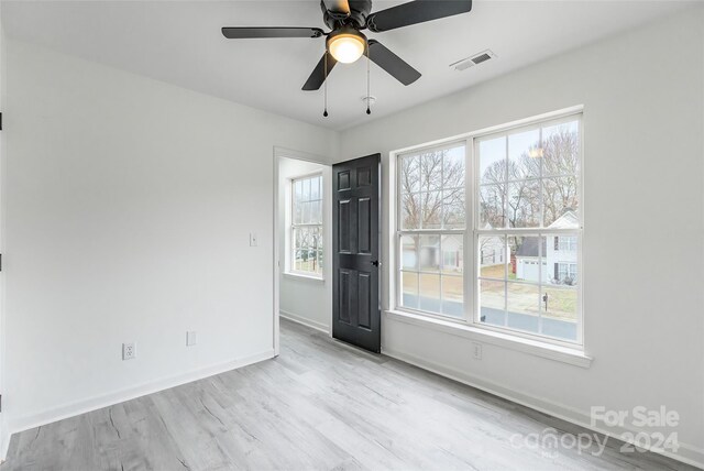 unfurnished room with ceiling fan, light wood-type flooring, and a wealth of natural light