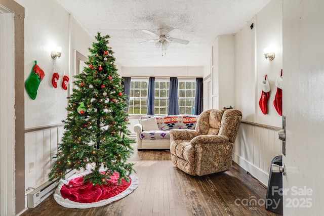 sitting room featuring hardwood / wood-style flooring, ceiling fan, a textured ceiling, and a baseboard heating unit