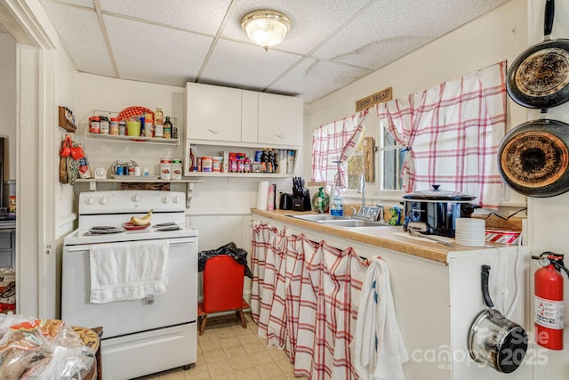 kitchen with white range with electric stovetop, a drop ceiling, white cabinets, and sink