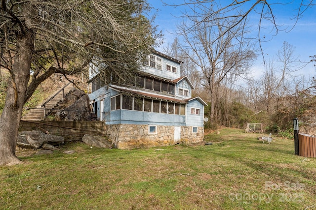 rear view of house with a sunroom and a yard