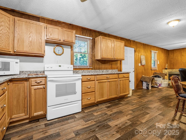 kitchen with a textured ceiling, wood walls, dark wood-type flooring, and white appliances