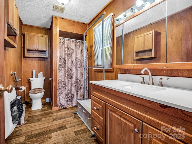 bathroom featuring vanity, heating unit, toilet, and wood walls