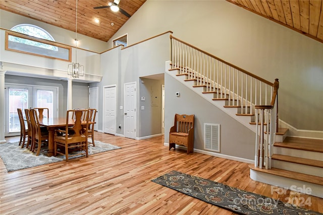 dining space featuring high vaulted ceiling, ceiling fan with notable chandelier, light hardwood / wood-style floors, wood ceiling, and decorative columns