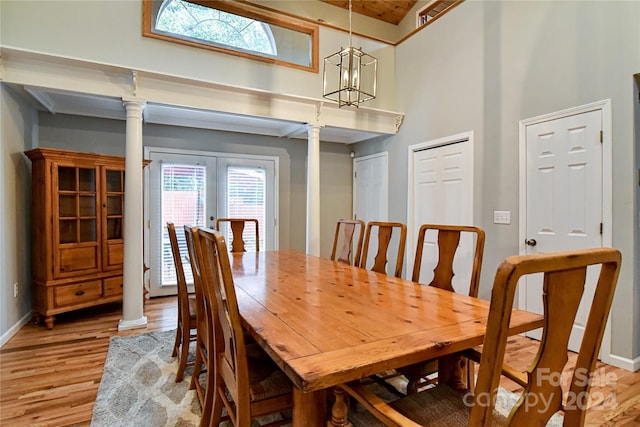 dining space featuring ornate columns, french doors, a high ceiling, light hardwood / wood-style flooring, and a chandelier