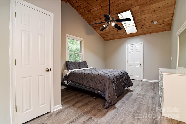 bedroom with vaulted ceiling with skylight, light hardwood / wood-style flooring, ceiling fan, and wood ceiling