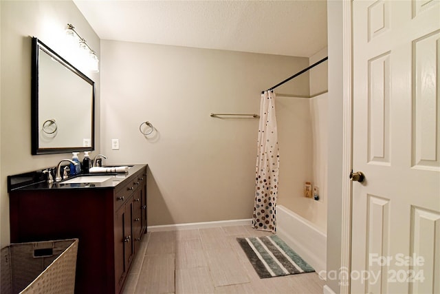 bathroom with tile patterned floors, vanity, shower / bath combo with shower curtain, and a textured ceiling