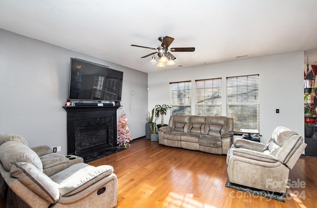 living room featuring wood-type flooring, ceiling fan, and a premium fireplace