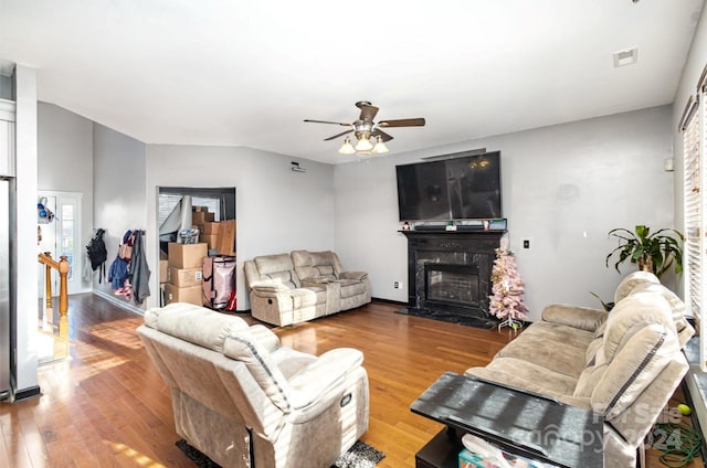 living room featuring ceiling fan, a premium fireplace, and light hardwood / wood-style flooring