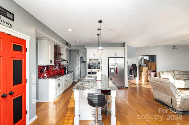 kitchen featuring decorative backsplash, a kitchen breakfast bar, dark stone counters, stainless steel fridge with ice dispenser, and hanging light fixtures