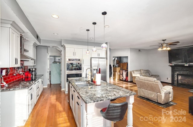 kitchen with sink, stainless steel appliances, dark stone countertops, pendant lighting, and white cabinets