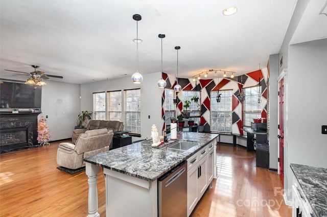 kitchen with sink, stainless steel dishwasher, pendant lighting, a kitchen island with sink, and white cabinets