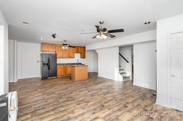 kitchen with hardwood / wood-style flooring, black refrigerator with ice dispenser, a kitchen island, and sink