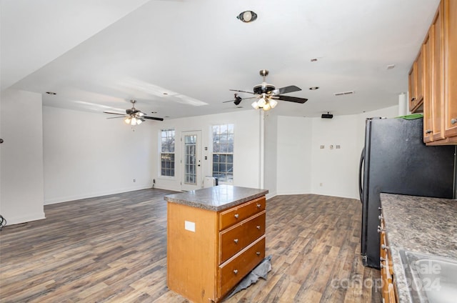 kitchen featuring black refrigerator, a kitchen island, ceiling fan, and dark wood-type flooring